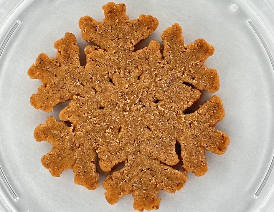Snowflake-shaped brown sugar cookie on a clear plate, close-up detail of the crumbly topping.