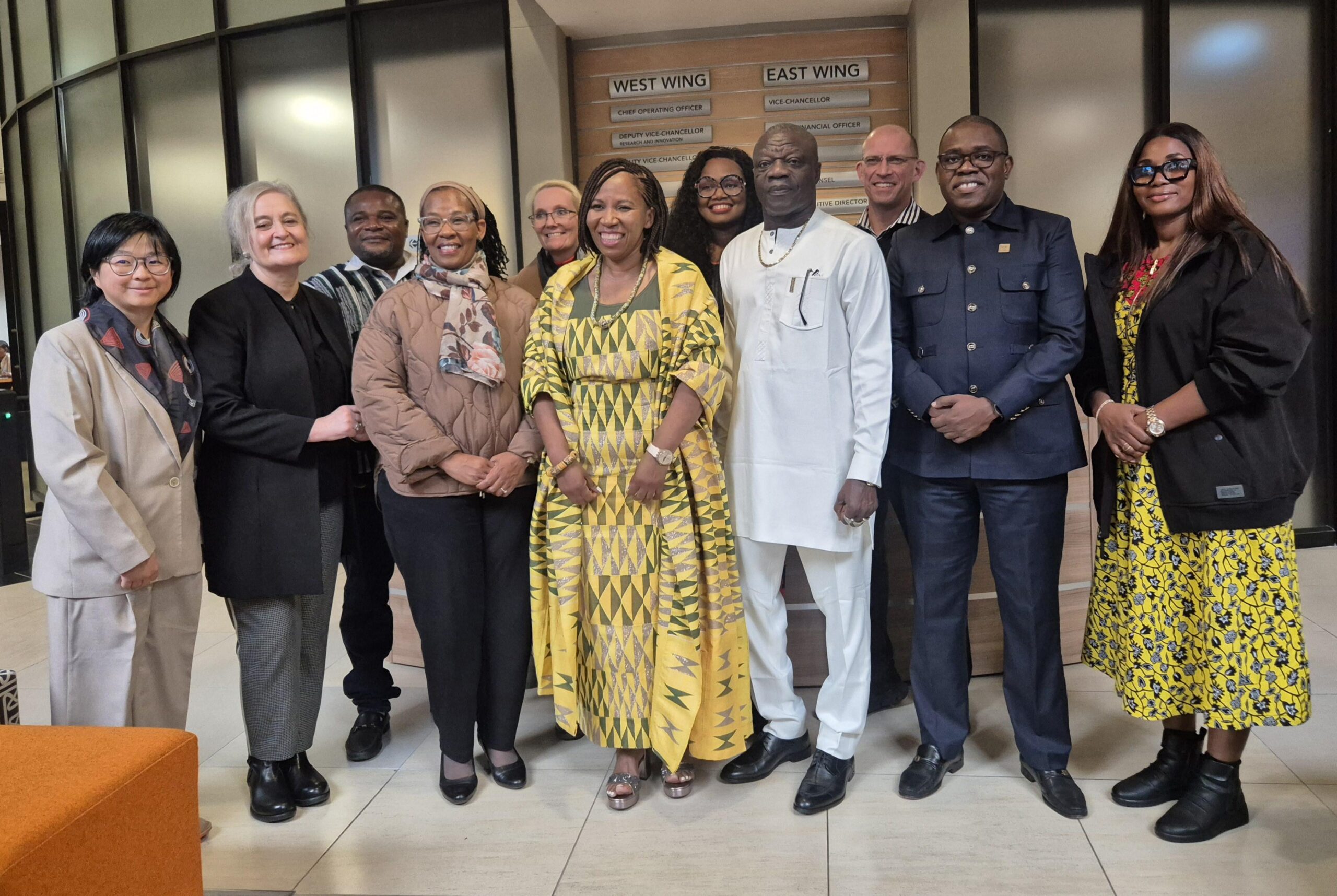 Ten people posing together in a hallway, smiling for the camera.