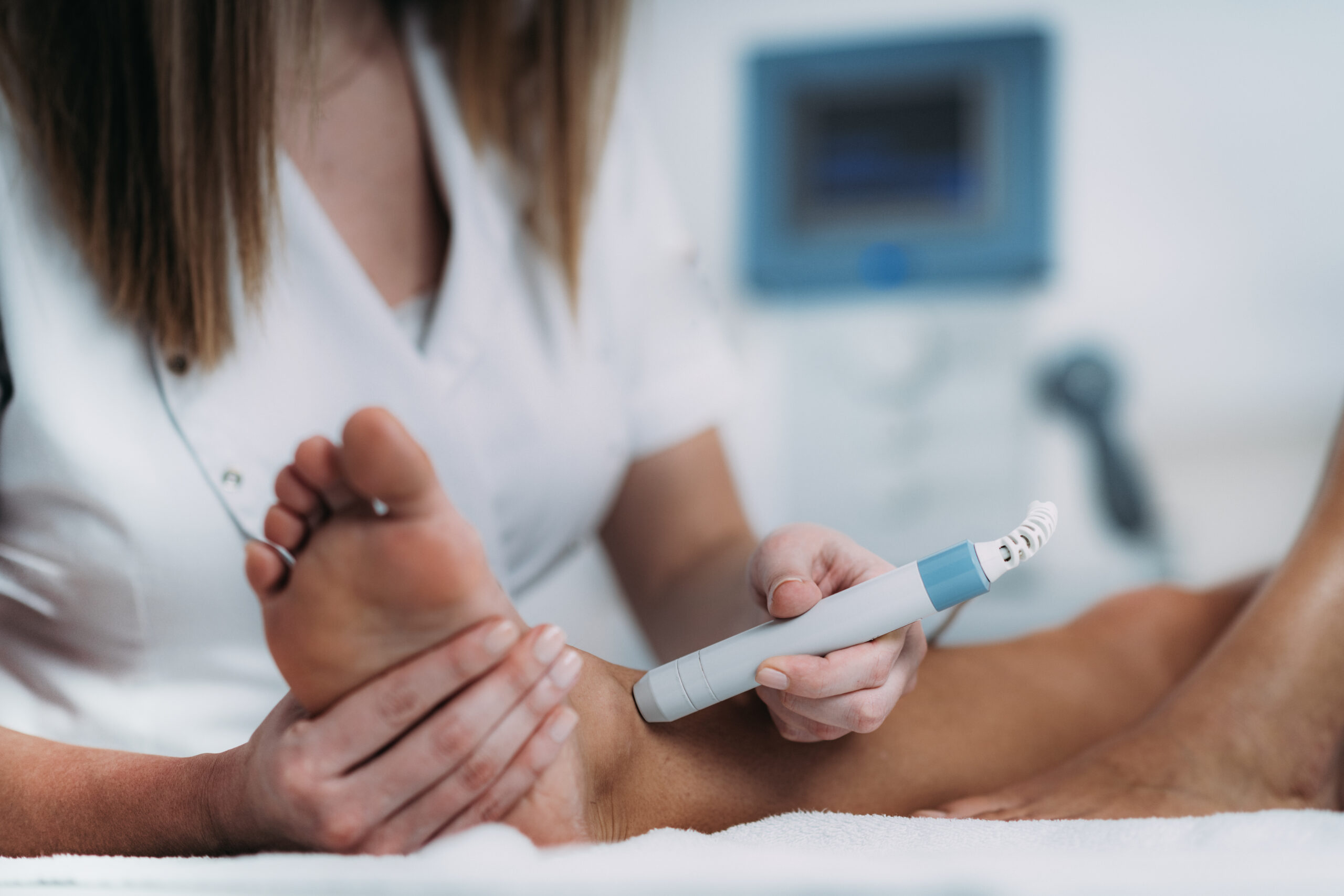Close-up of hands holding a medical syringe, with a clinician in white in the blurred background.